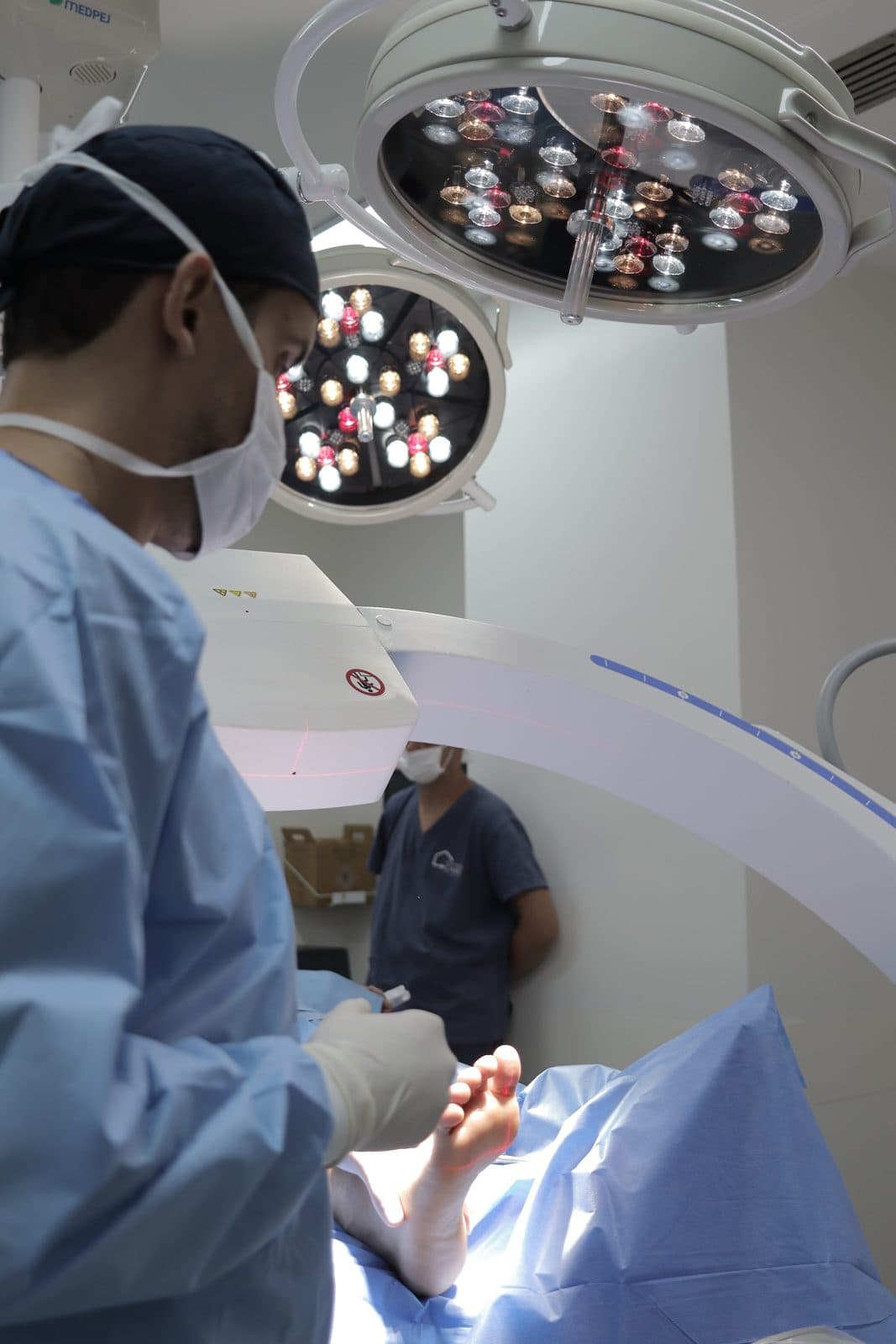 Dr. Pedro Barreto operando um pé no centro cirúrgico, sob os focos de luz